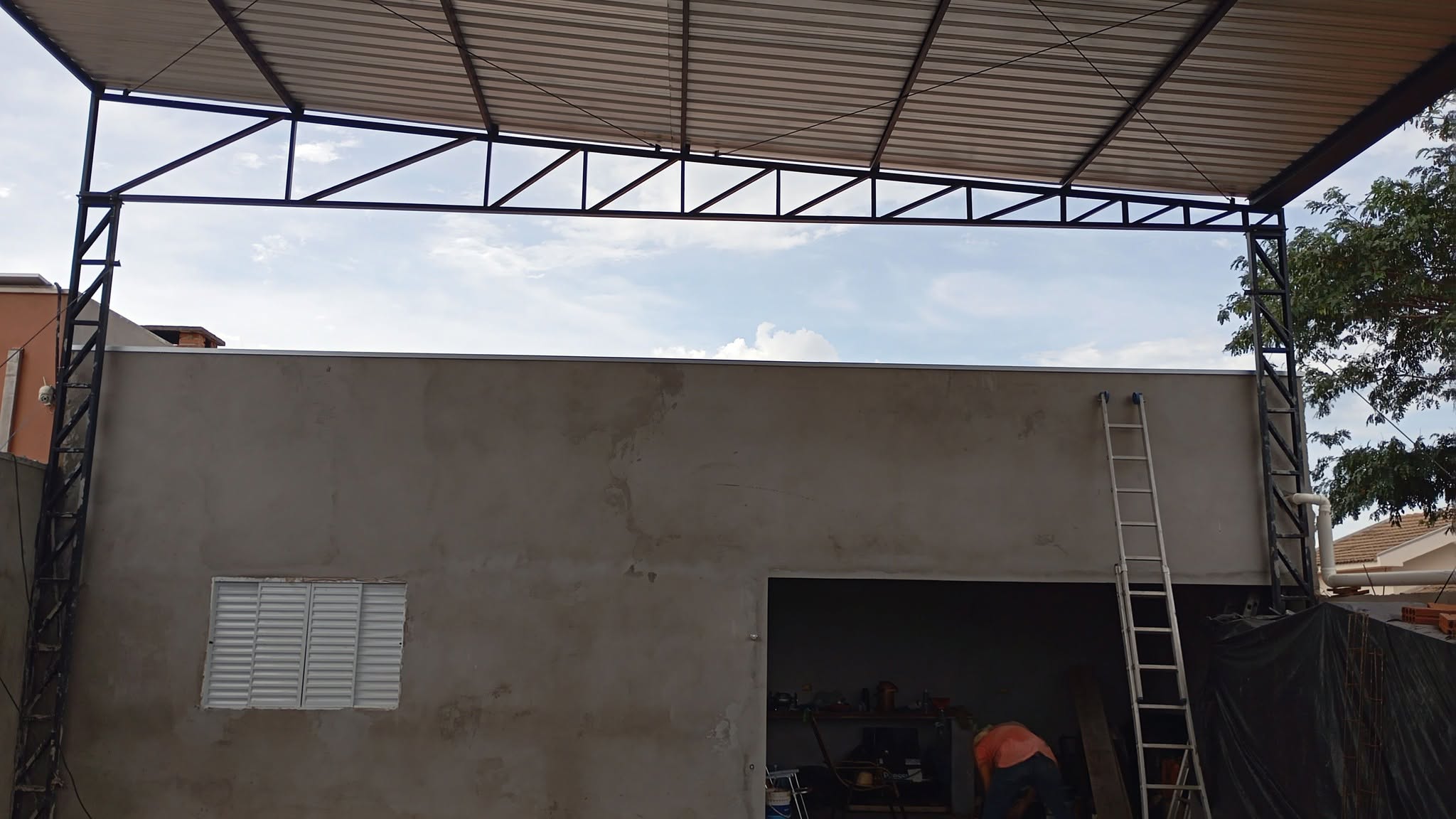 Estrutura metálica preta com cobertura sobre garagem em construção