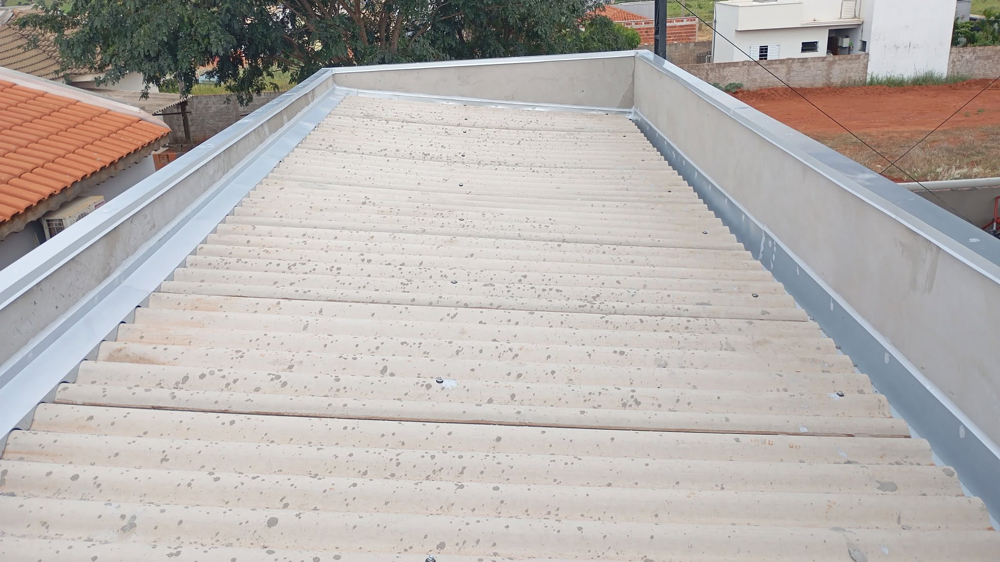 Calha galvanizada instalada na beira de telhado de fibrocimento